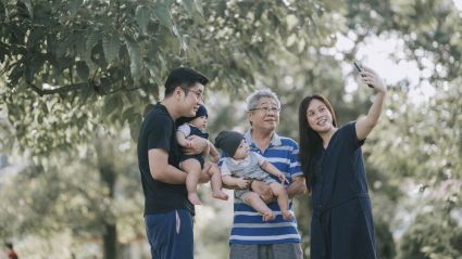 Family taking a selfie together in a sunny park.