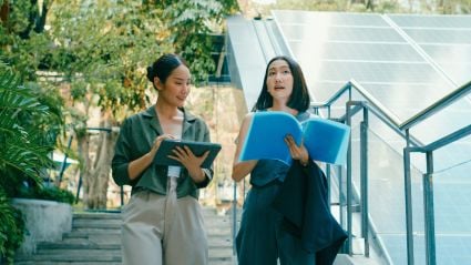 Two colleagues review documents in front of solar panels, highlighting collaboration in clean energy innovation.