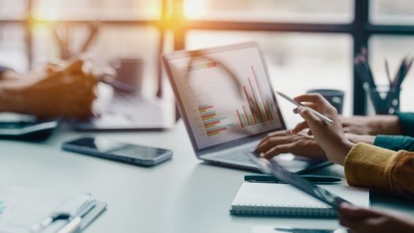 People reviewing colorful bar charts and data visualizations on a laptop in a bright, modern workspace—highlighting research and insights.