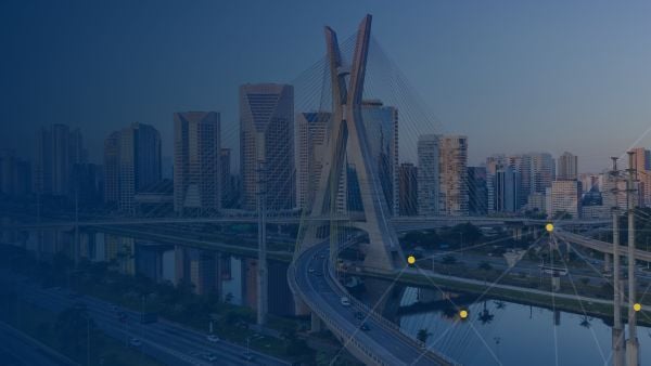 View of São Paulo’s Octavio Frias de Oliveira Bridge with modern high-rise buildings in the background, under a clear sky.