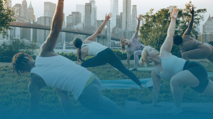 A group of people do yoga outside in a park together