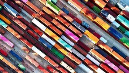 Aerial view of colorful shipping containers neatly arranged in rows at a port or storage yard.