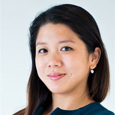 Portrait of Ann Marie Eu, director on the Business and Program Development team at the Milken Institute. She has long dark hair, is wearing a dark teal top, and small drop earrings. She is smiling slightly and looking confidently at the camera against a light background.