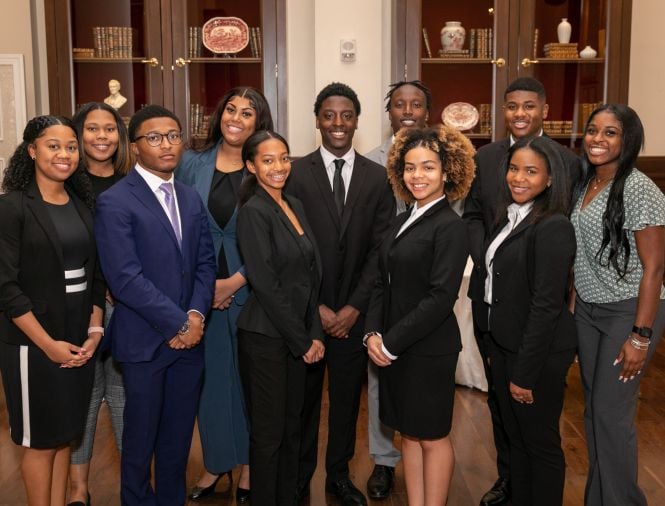 a group of 11 young black students professionally dressed in formal room