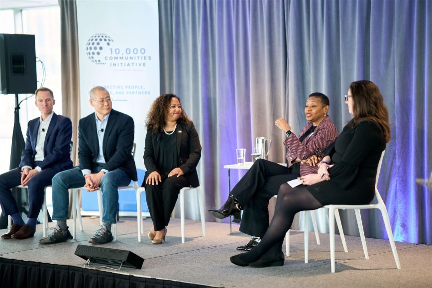 A diverse group of people sit on stage in a discussion