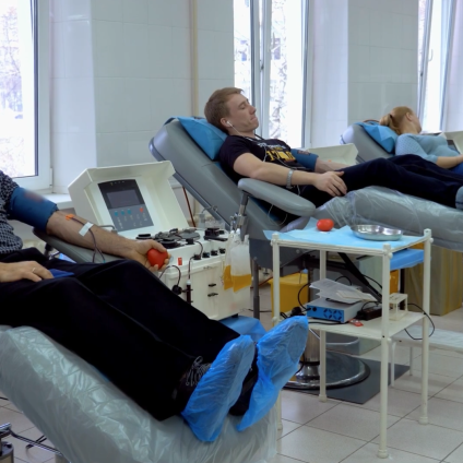 three people donating blood in a medical facility
